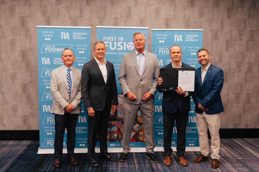 Tennessee Governor Bill Lee stands inside a hotel conference room with a group of officials from Type One Energy and TVA in front of a sign that reads "First in Fusion."   